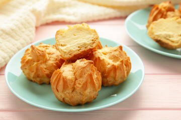 Homemade profiteroles with cream on plate on pink background. Fresh baked golden profiterole.