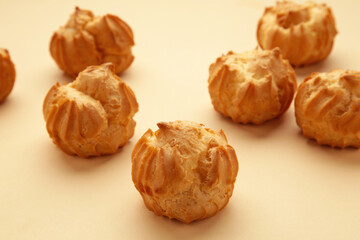 Homemade profiteroles with cream on beige background. Fresh baked golden profiterole.