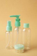 Empty travel cosmetic bottles on beige background. Minimalist bodycare beauty products for vacation or journey. Top view. Copyspace.