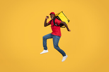 Fototapeta na wymiar Happy excited fast young african american delivery man in uniform with backpack and open mouth has fun