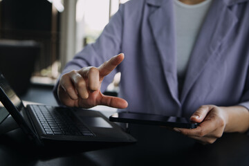 Asian Business woman using calculator and laptop for doing math finance on an office desk, tax, report, accounting, statistics, and analytical research concept