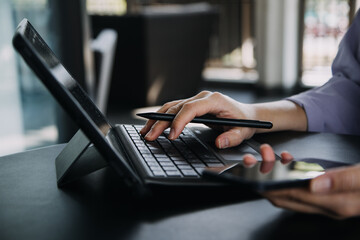 Asian Business woman using calculator and laptop for doing math finance on an office desk, tax, report, accounting, statistics, and analytical research concept