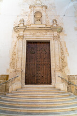 Fototapeta na wymiar Stairs and wooden door at the entrance of the church of Banyeres, Alicante (Spain).