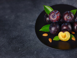 Sweet plums on dark background. Fresh blue plums with leaves. Food fruit Background. Summer postcard. Harvesting in garden, Harvest of plum