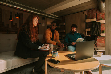 Cute redhead female worker has issues with her daily task at work. She is asking for help her two male multiracial colleagues