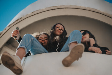 Low angle view of three lovely girls with slight smile on their faces, looking at the camera