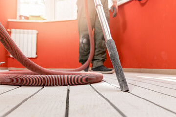 Construction worker use vacuum cleaning concrete floor for Install underfloor heating electrical...