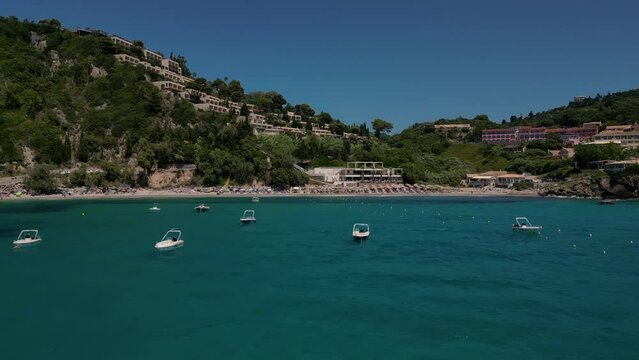 Drone footage of boats gently swaying in the sunny sea, moored not far from the Paralia Ermones Beach, on a hot day