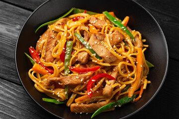 Stir fry chow mein noodles with pork and vegetable in black bowl. asian style food