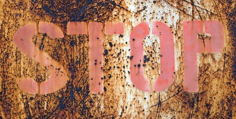 A stop sign on a rusty metal fence, conceptual image for danger.