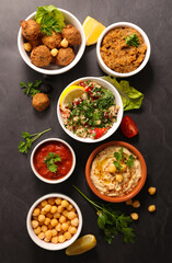 Assorted Middle Eastern and arabic dishes on a dark background- hummus, tabbloueh,salad,falafel