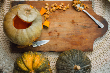 top view of decorative background with pumpkin on cutting board, with seeds and knife on table with copy space. concept of halloween and thanksgiving.