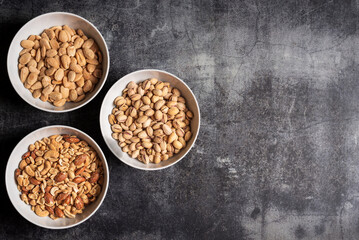 Bowls with nuts, almonds, pistachios and a mix of peanuts, cashews, hazelnuts and roasted almonds, top view.