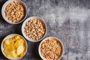 Bowls with chips and nuts, almonds, pistachios and a mix of peanuts, cashews, hazelnuts and roasted almonds, top view.
