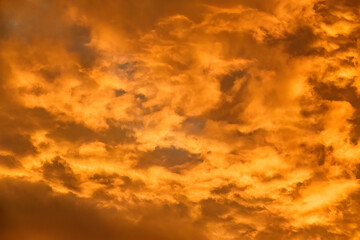 Fiery sky, in shades of orange, at sunset or early twilight, for background or element with motifs of summer and heat waves, illumination, transition