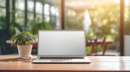 Image of an open laptop on a desk, white screen, a sunlit office blurred in the background, copy...