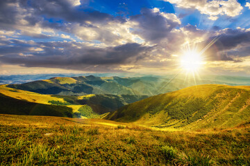 Fototapeta premium green grass on rolling hillside meadow in high mountains under the cloudy blue sky at sunset. beautiful countryside scenery in evening light. carpathians, ukraine.