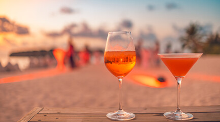 Two cocktail drinks blur beach coast party people and colorful sunset sky in background. Luxury...
