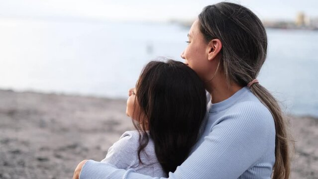 4k video of mother and daughter watching the sunset and enjoying the company together. Concept: maternity, bond, adhesion