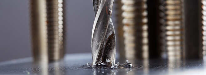 metal drill bit with lubrication oil liquid make holes in steel billet on industrial drilling...