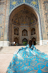 Young woman in traditional Uzbek dress at Ulug bek madrassah, Registan square in Samarkand,...