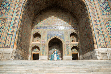 Fototapeta na wymiar Uzbek woman in traditional dress in Registan square Samarkand, Uzbekistan