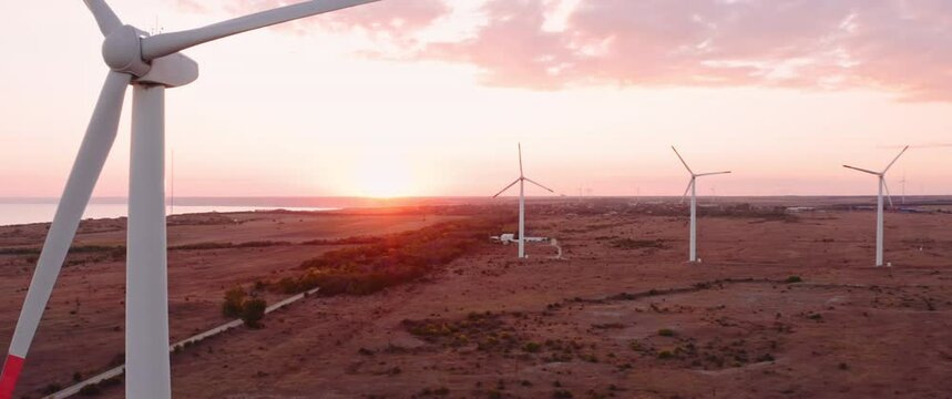 Cinematic drone take off Aerial view of wind turbines farm in sunset time with clouds. Anamorphic 2.39 scope