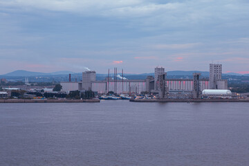 Naklejka premium The port skyline seen from the south shore during a cloudy summer dusk, Quebec City, Quebec, Canada