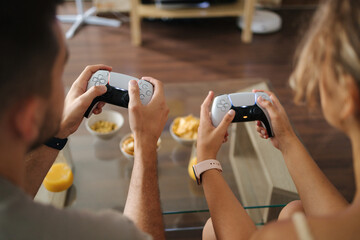 First person view of couple using joysticks to play video games on console 