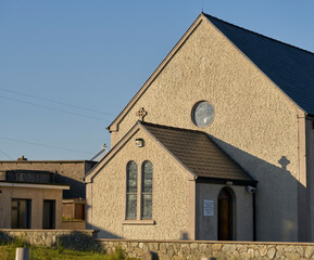 As the sun sets on the gable of a church, it casts a shadow of the cross on a wall, taken at Achill island, Co. Mayo Ireland.