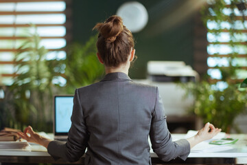 business owner woman in grey business suit at work meditating