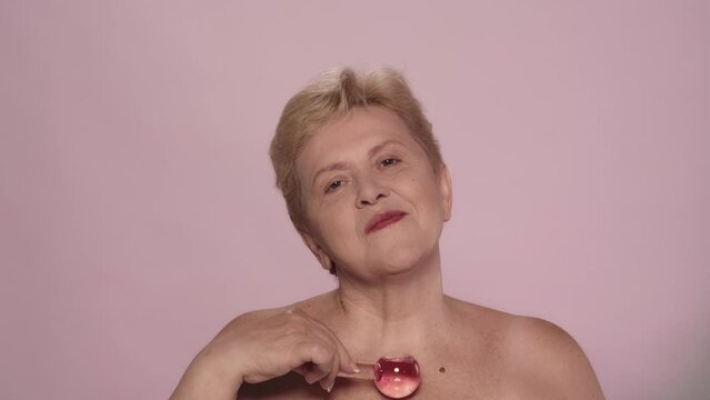 Beautiful blonde senior woman making a massage with a cryosphere glass globes with gel, close up shot