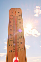 Wooden outdoor thermometer background scorching summer sun and blue sky.