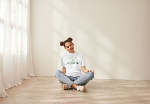 Mockup of woman wearing customizable color t-shirt with design, sitting on floor