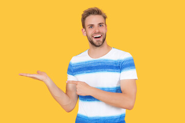 man in his summer tshirt offer sale. man offering take advantage of the summer sale prices. man looks positive advertising summer sale isolated on yellow. banner advertisement of summer sale by man