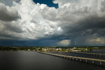 Fototapeta na wymiar Heavy thunderstorm approaching traffic bridge connecting Punta Gorda and Port Charlotte over Peace River. Bad weather conditions for driving during rainy season in Florida