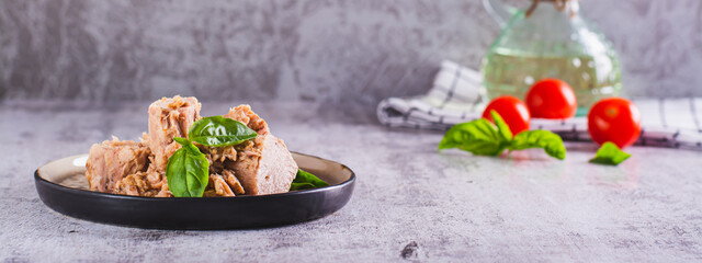 Pieces of canned tuna fish and basil leaves on a plate web banner