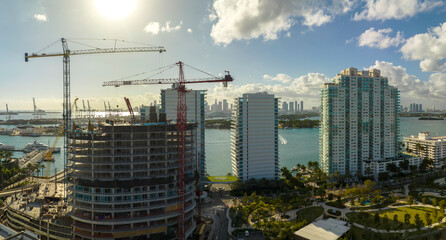 Fototapeta na wymiar New construction site of developing residense in american urban area. Industrial tower lifting cranes in Miami, Florida. Concept of housing growth in the USA