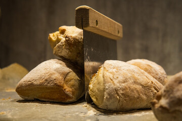 A pile of freshly baked bread buns and a dough scraper in the middle. Close up photo. Home baking concept. Rustic.