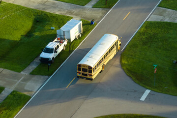 Top view of classical american yellow school bus driving on rural town street for picking up kids...