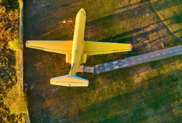 Yellow passenger plane stands in the field. Top view with a drone