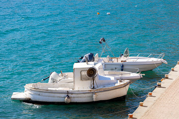 A fishing boat is moored near the pier, a white boat for catching fish with nets.