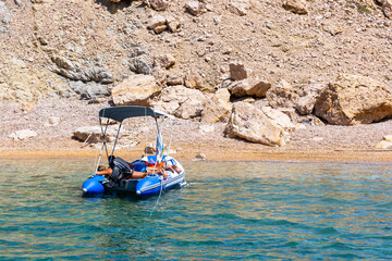 Seascape with boats near the beach. A deserted island and a moored motor lonely boat