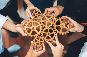 Office worker holding cog wheel as unity and teamwork in corporate workplace concept. Diverse...