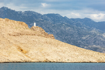 Blue sea and islands with a lighthouse on the edge of a mountain, landscape photography by the sea on a sunny day