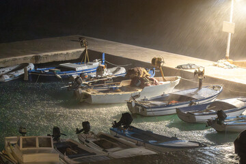 Fishing boats moored during heavy rain, storm at night, sea