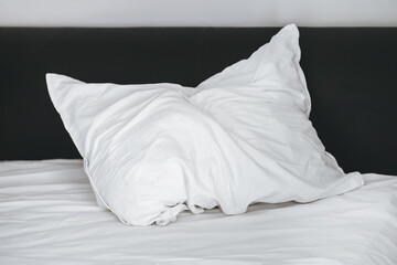 Fototapeta na wymiar A crumpled white pillow lies on the bed after sleeping
