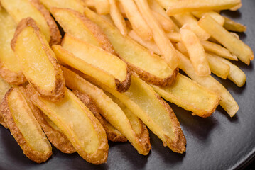 Delicious crispy french fries with salt and spices on a textured concrete background