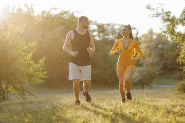 Foto op Canvas A dedicated personal trainer, a young man, is actively coaching and motivating a sportswoman, a female athlete, during their invigorating outdoor jogging session. © Alexandr
