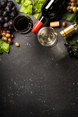 Wine set at black background. White and red wine, Glass of wine, bottle and fresh crape. Top view with copy space.